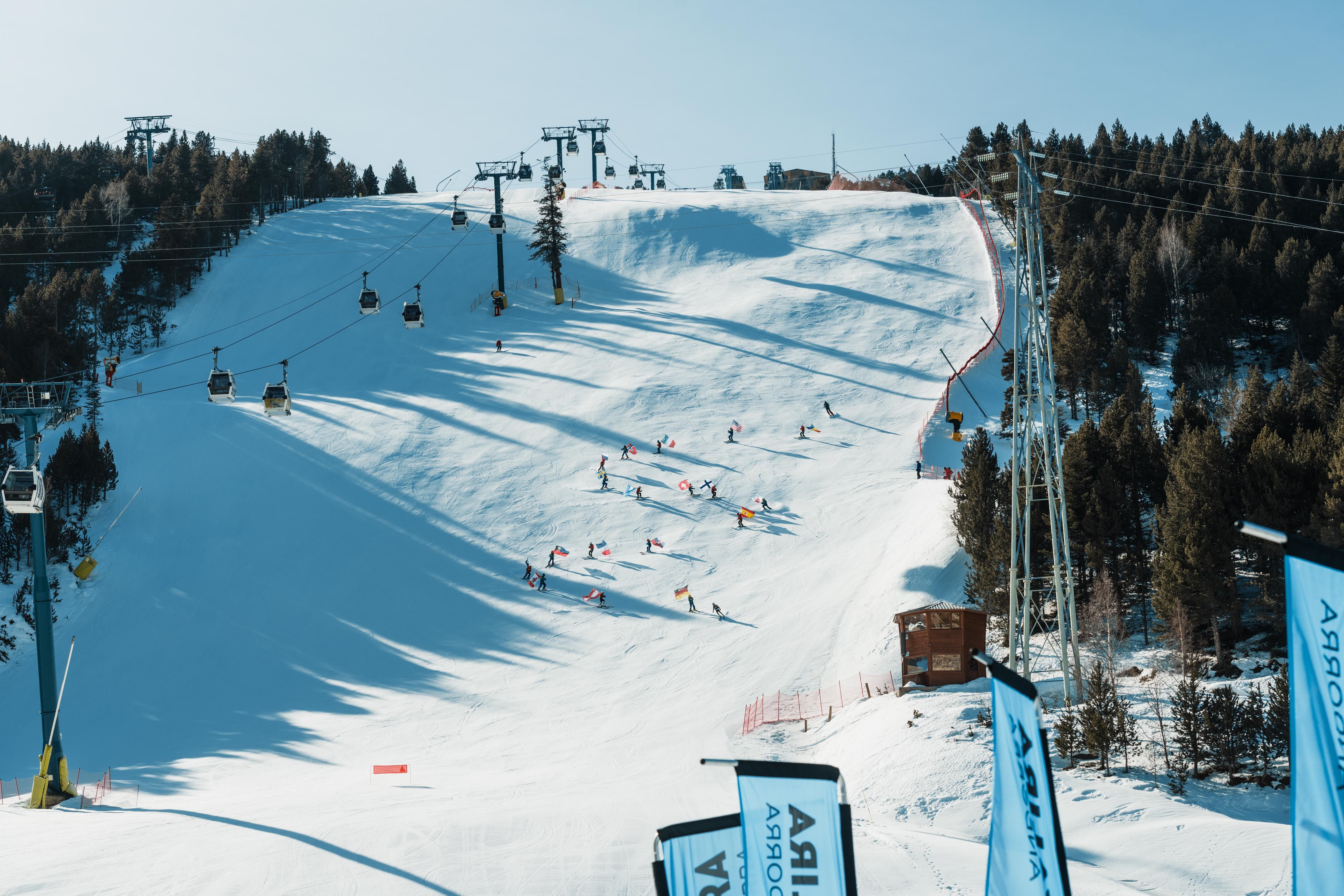 Els infants nascuts el 2012 baixant amb les banderes per la pista.