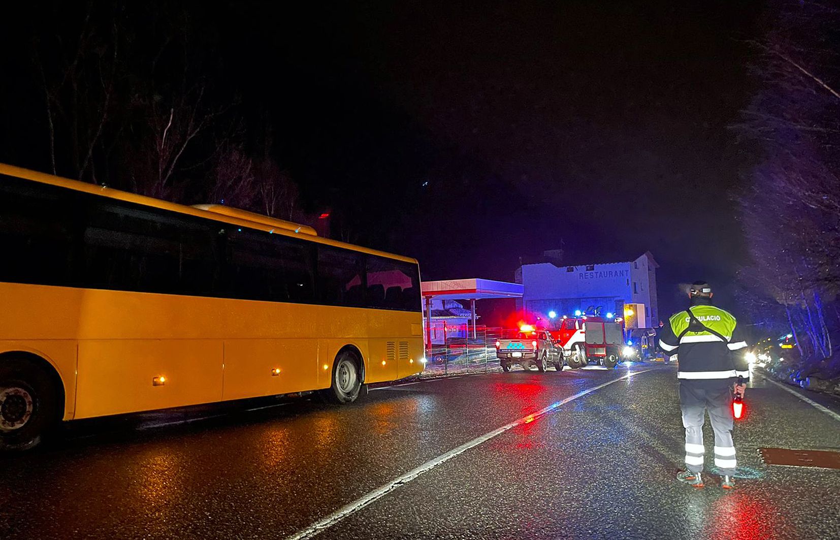 El bus afectat, a l'esquerra, i, al fons, els bombers, amb un agent de circulació en primer terme.