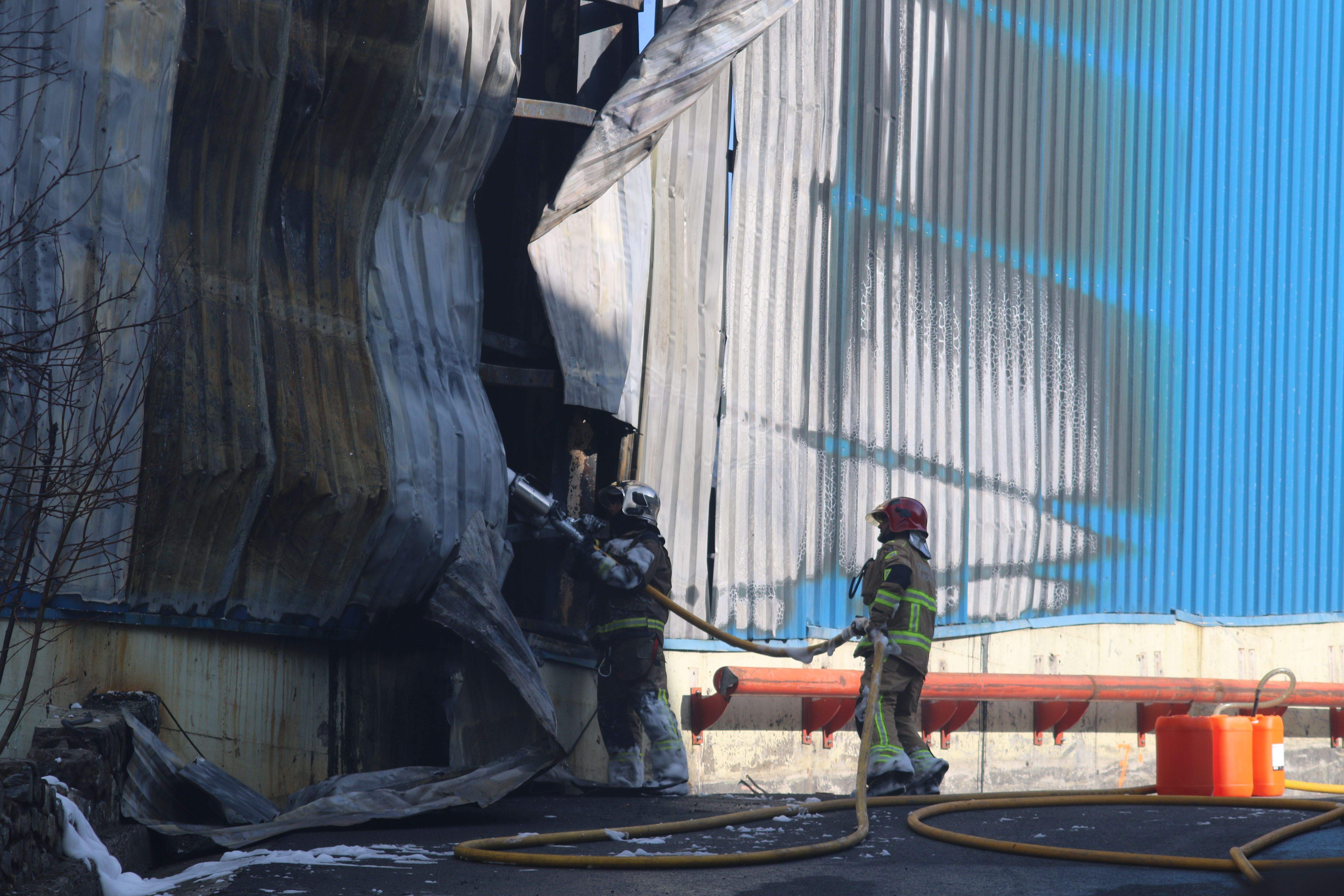 Dos bombers llançant aigua a l'interior de la nau.