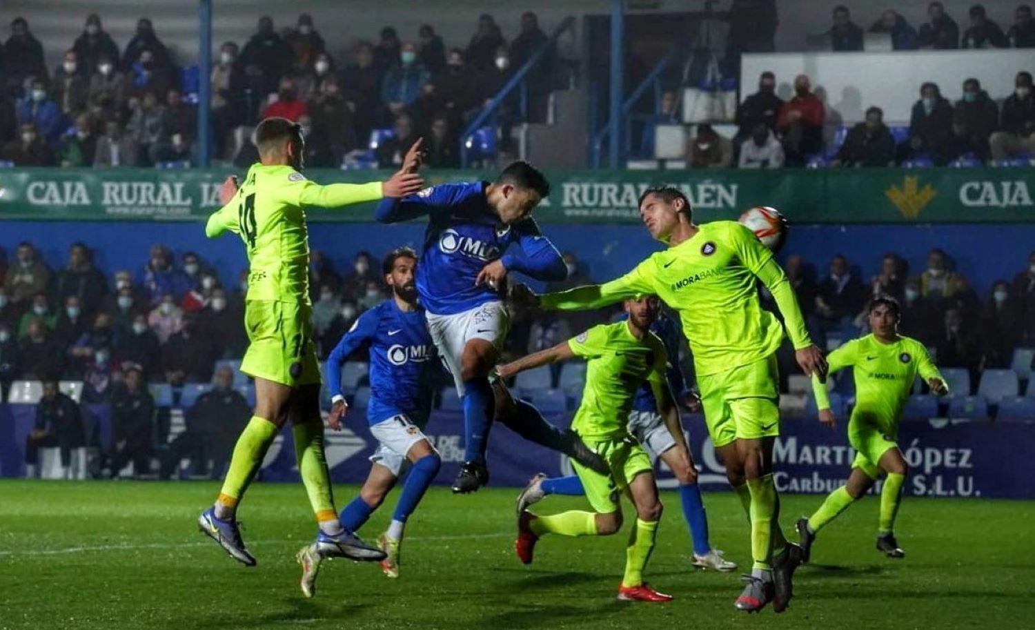 Un jugador del LInares remata de cap davant la pressió de la defensa de l'FC Andorra.