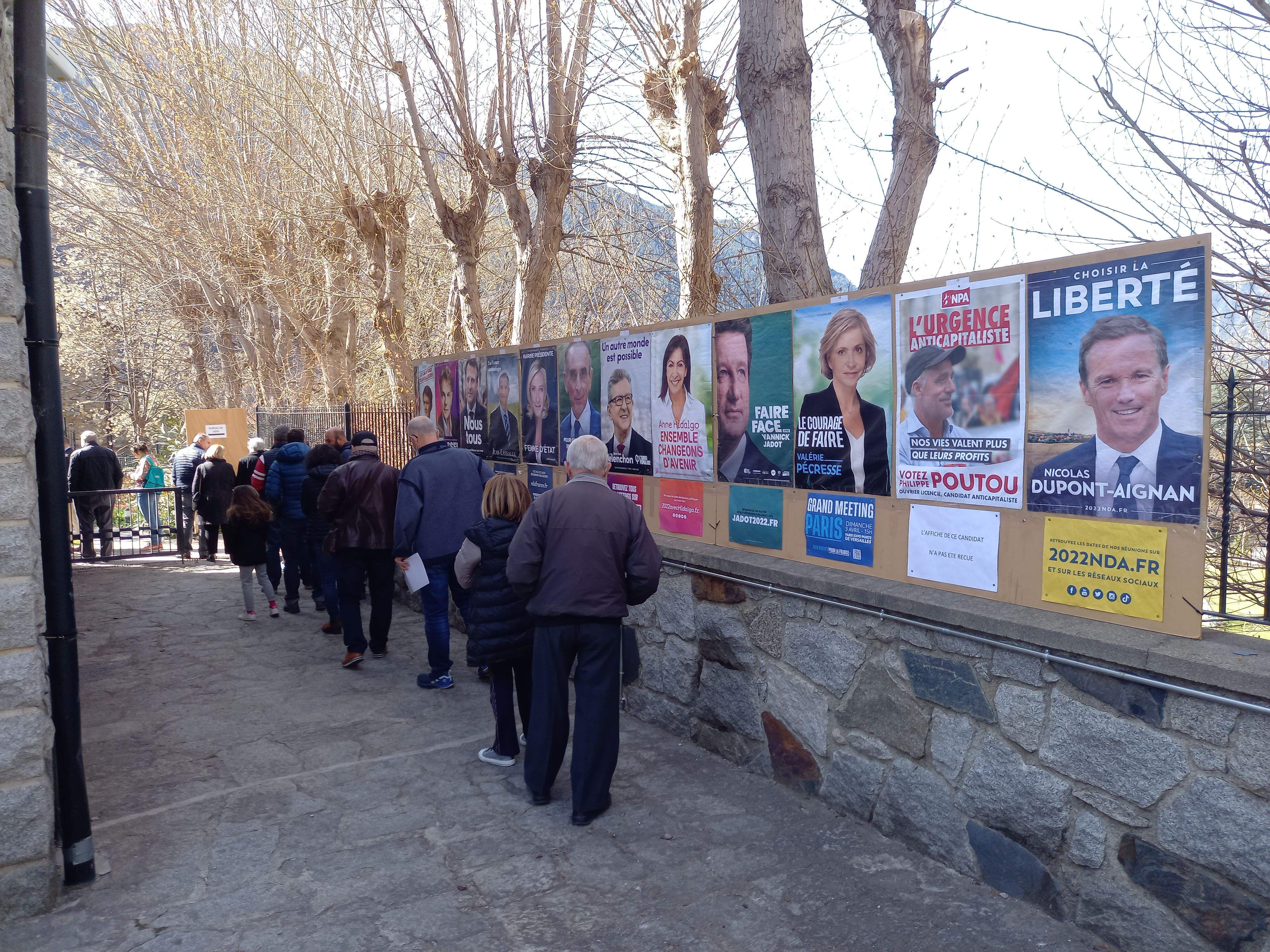 Cues de gent al costat dels cartells electorals.